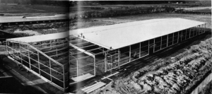 En modern industribyggnad skjuter snabbt i höjden. När detta läses är det nya surte-lagret redan färdigt att tas i bruk. Mannarna på taket är fr v Gideon Skoog, Barry Asplund, Jonas Olsson, och Einar Andersson. Nedan: to-talvy över den imponerande byggnaden. Man får ett begrepp om dess storlek, när man jämför den med männen på taket. Det är samma man-nar som på bilden ovan.